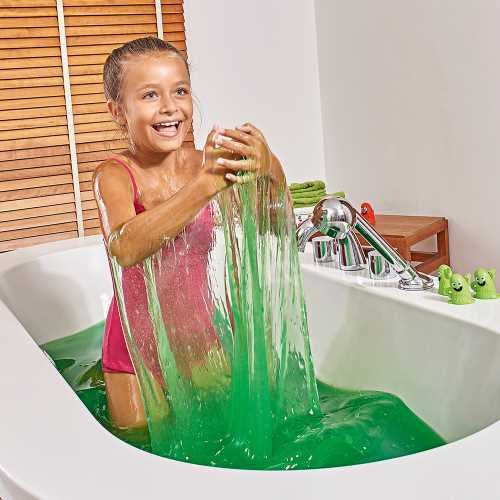 Uma menina a brincar alegremente na banheira com o ZIMPLIKIDS Slime para banho Baff Verde, deixando o slime escorrer pelas suas mãos.
