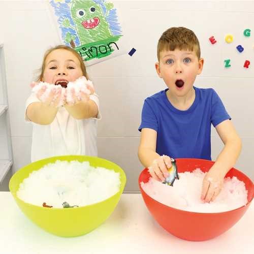Duas crianças sorridentes a interagir com as ZIMPLIKIDS Bolas de Neve em tigelas, desfrutando da brincadeira em casa.