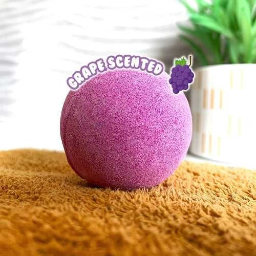 Uma bomba de banho esférica roxa ZIMPLIKIDS com a indicação "Grape Scented", pronta para uso na banheira.