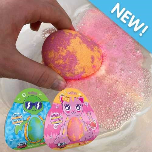 Uma mão a colocar uma bomba de banho ZIMPLIKIDS efervescente na água da banheira, com duas embalagens (gato e tartaruga) em primeiro plano.