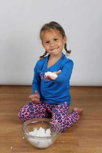 Menina sorridente a segurar uma bola de neve artificial ZIMPLIKIDS, pronta para a diversão e brincadeira imaginativa.