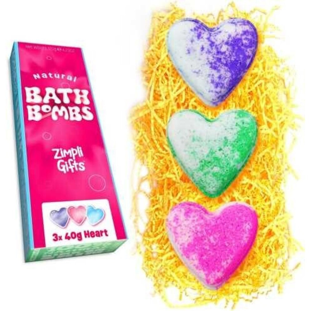 Pack de presente ZIMPLIKIDS com 3 bombas de banho em forma de coração, nas cores roxo, verde e rosa, apresentadas sobre papel picado amarelo vibrante.