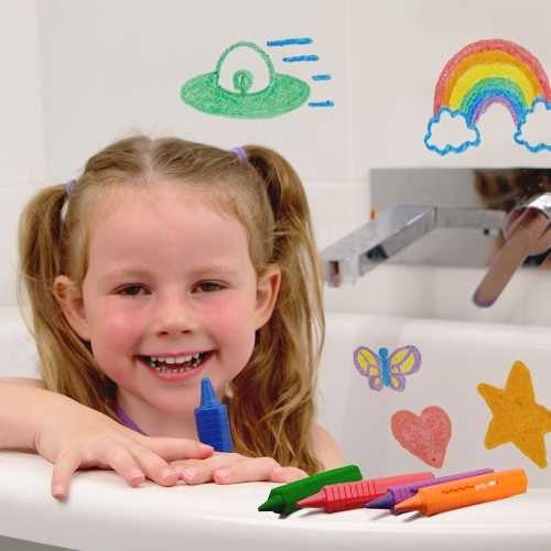 Criança sorridente a brincar na banheira com os marcadores Zimplikids, desenhando um arco-íris e um OVNI nos azulejos.