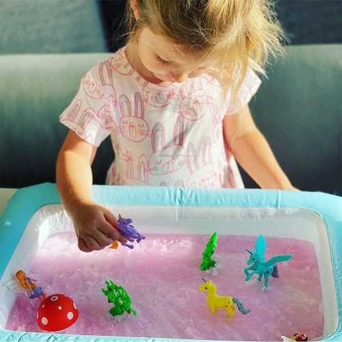 Duas crianças pequenas agachadas a brincar com o ZIMPLIKIDS Pack Fantasy Gelli Worlds numa bandeja insuflável azul, cheia de gel cor-de-rosa e figuras.