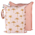 Duas bolsas reutilizáveis da Tiny Twinkle com padrão de palmeiras douradas sobre fundo rosa claro, uma delas parcialmente visível atrás, em tom rosa liso.