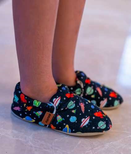 Pés de criança a usar as pantufas Slip Stop Mars sobre um chão de mármore claro.