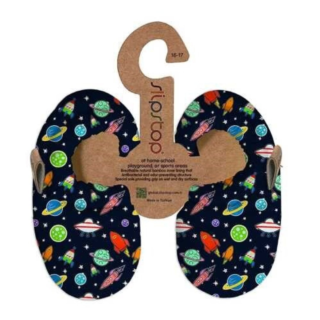 Pantufas Slip Stop com padrão espacial de foguetões e planetas, apresentadas no seu suporte de cartão.