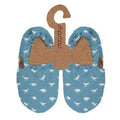 Par de pantufas infantis azuis com padrão de dinossauros brancos, apresentadas em cabide de cartão com a marca SlipStop.