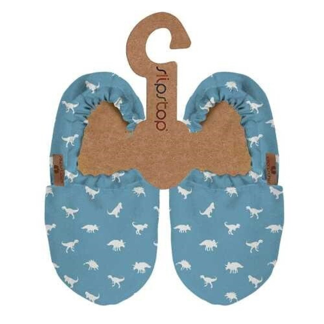 Par de pantufas infantis azuis com padrão de dinossauros brancos, apresentadas em cabide de cartão com a marca SlipStop.