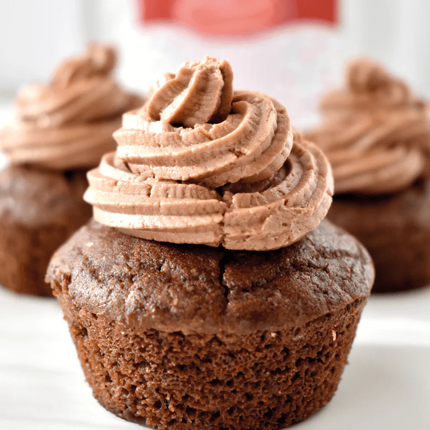 Um cupcake em primeiro plano com cobertura espiralada de buttercream de chocolate Fidu, sobre uma base de bolo de chocolate escuro.