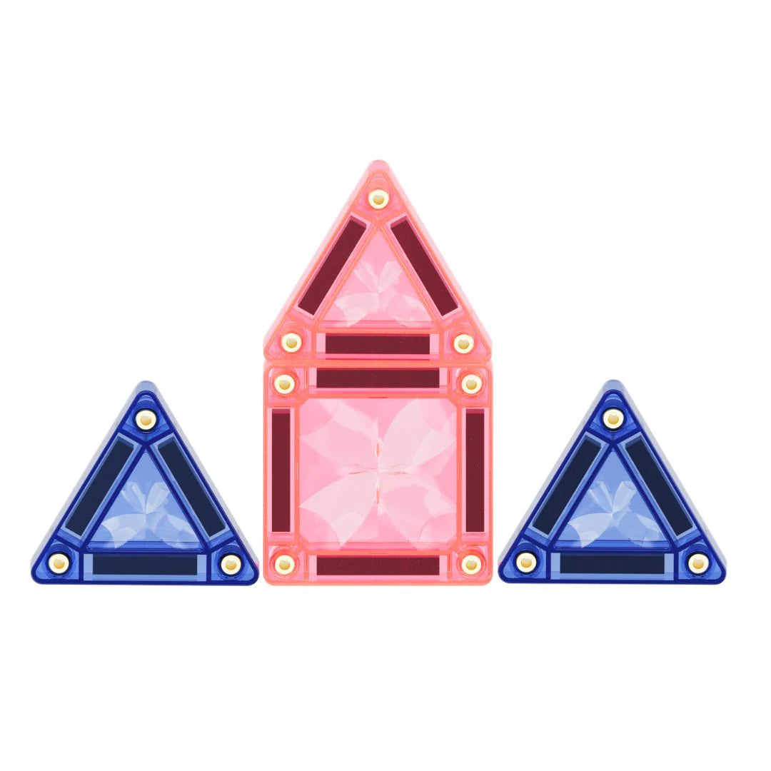 Três blocos magnéticos Clever Clixx em tons pastel, com uma forma de casa rosa ao centro e duas pirâmides azuis.