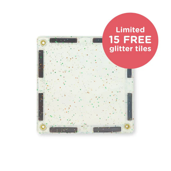 Detalhe de uma peça magnética Clever Clixx transparente com glitter verde e dourado, destacando os ímanes.
