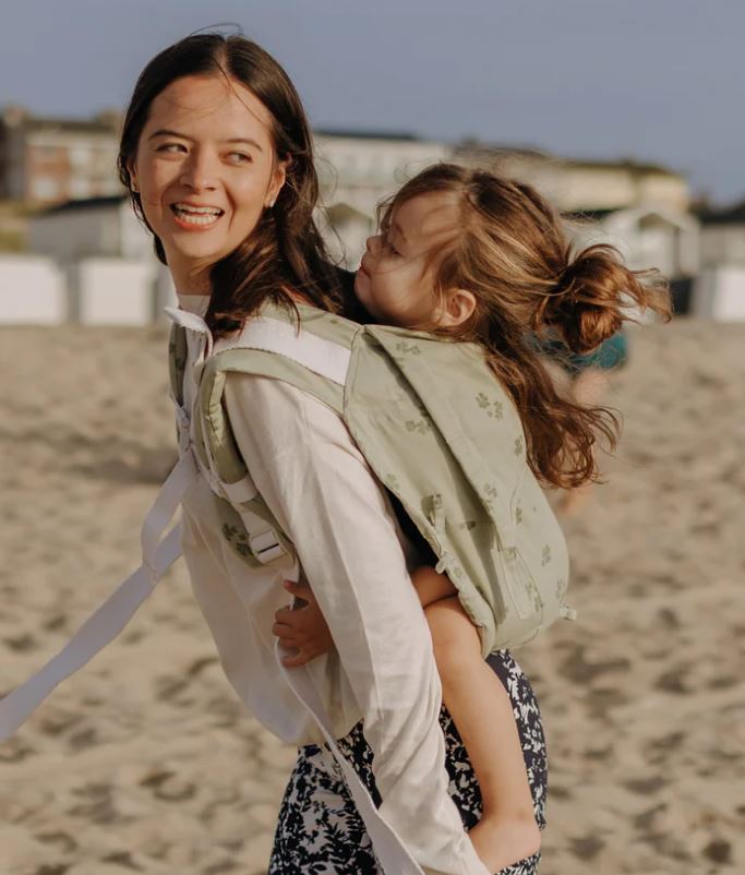 Mãe e filho na praia, ambos a sorrir, com o filho a ser carregado no Onbuhimo Fidella.