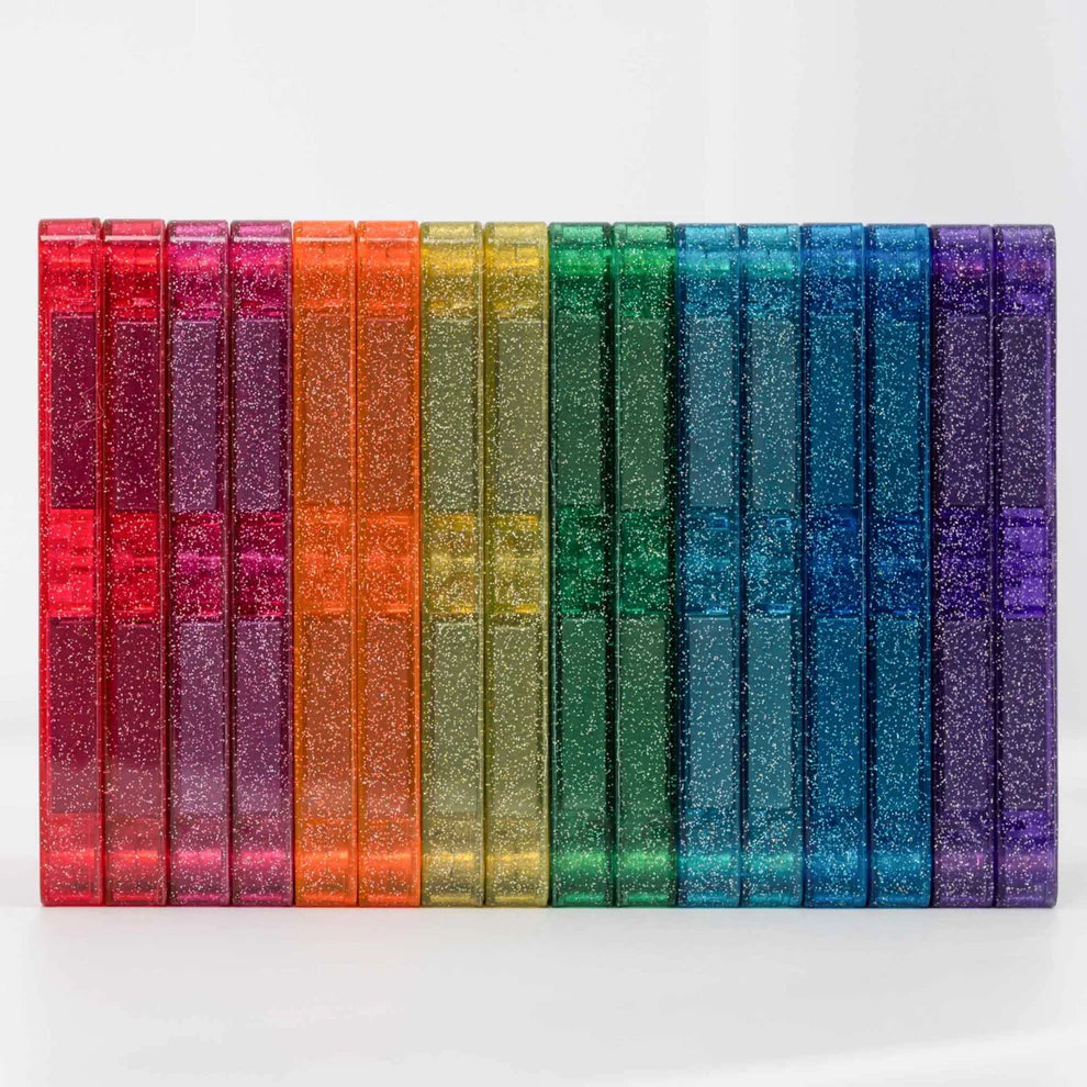 Vista lateral de várias peças magnéticas Connetix Glitter Castle Pack, alinhadas em cores do arco-íris com brilho.