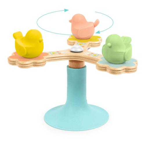 Detalhe do brinquedo Djeco BabySpini com três patinhos coloridos (amarelo, rosa, verde) a girar sobre uma base azul com ventosa.