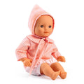 Boneca Rosa da Djeco Pomea sentada, com olhos castanhos expressivos, vestindo um conjunto rosa axadrezado e uma touca a condizer.