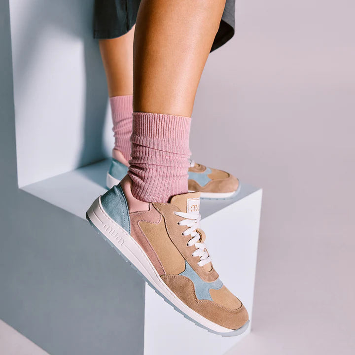 Close-up dos pés de uma pessoa em pé, usando as sapatilhas MUM Barefoot Daniela Cloud com meias rosa, destacando o design e as cores.