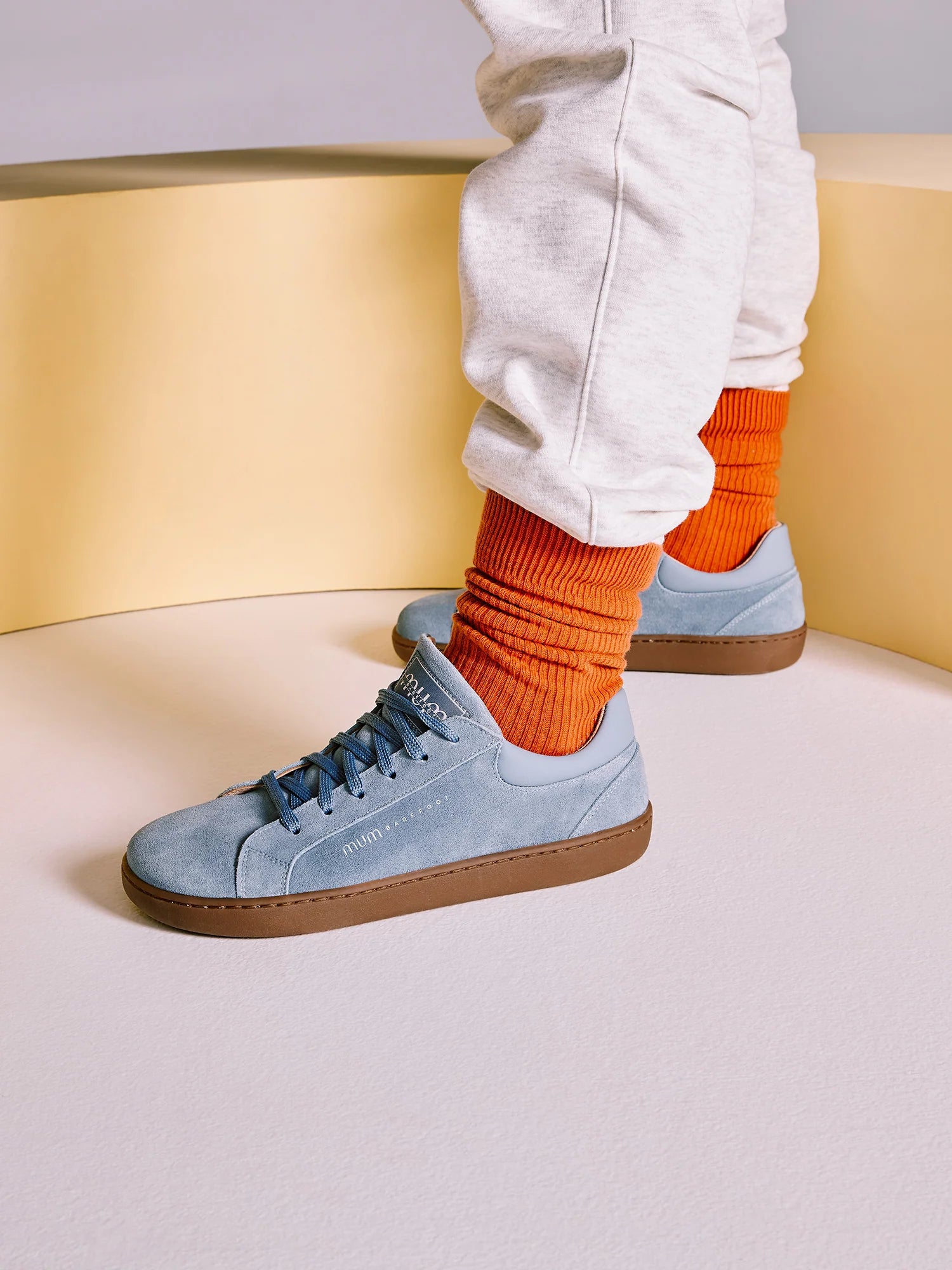 Detalhe das sapatilhas MUM Barefoot Diana Sky nos pés de uma pessoa, com meias cor de laranja, realçando o design e a flexibilidade.