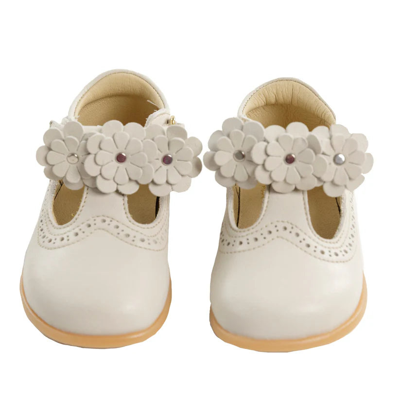 Par de sapatos Bunny Barefoot Pantera Creme, vista frontal, com acessórios de flores decorativas nas tiras, realçando a personalização.