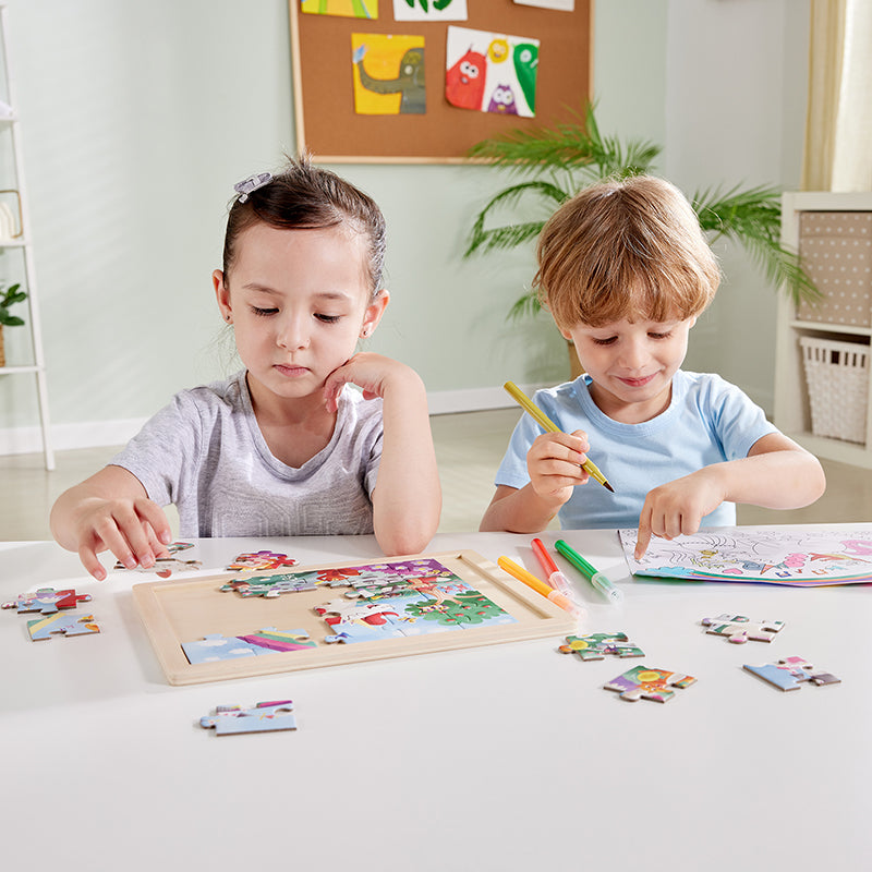 Crianças concentradas a montar o Hape Puzzle de madeira Unicórnio 2 em 1 e a colorir um desenho separado.