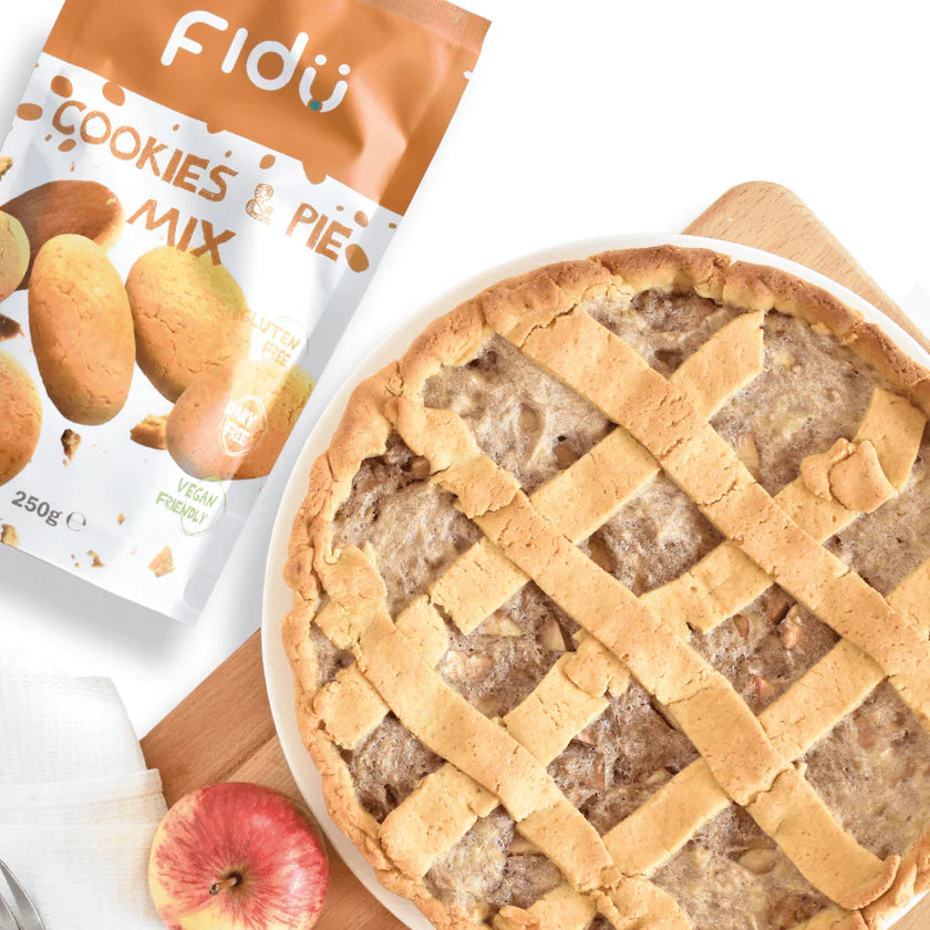 Embalagem do Fidu Preparado Bolachas e Tarte s/ glúten ao lado de uma tarte doce de maçã com cobertura em treliça, pronta a servir.