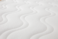 Detalhe da superfície acolchoada branca do Colchão de molas Micuna, evidenciando o padrão ondulado e a textura suave.