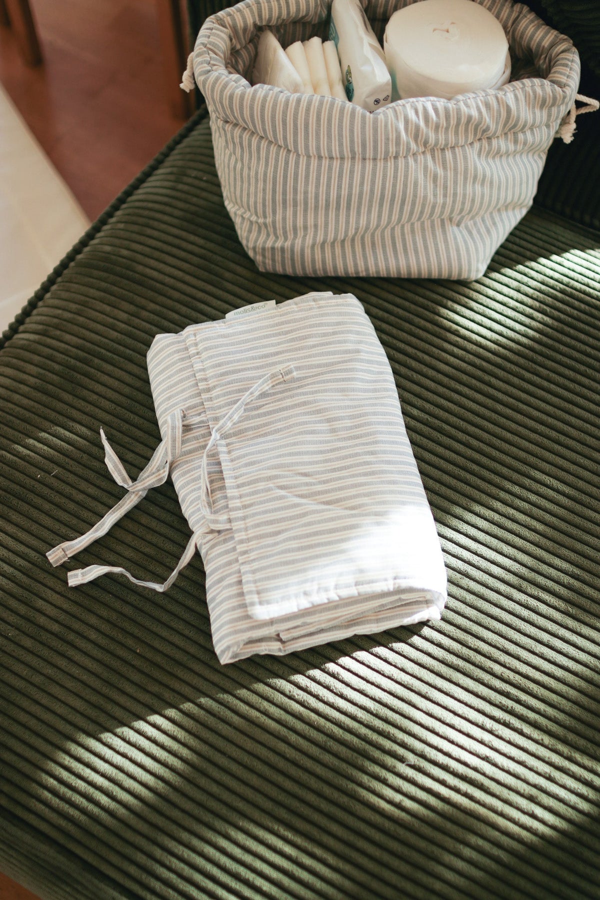 Muda-fraldas portátil MolisandCo Blue Stripes em uso, a servir de superfície macia para mudar a fralda ao bebé