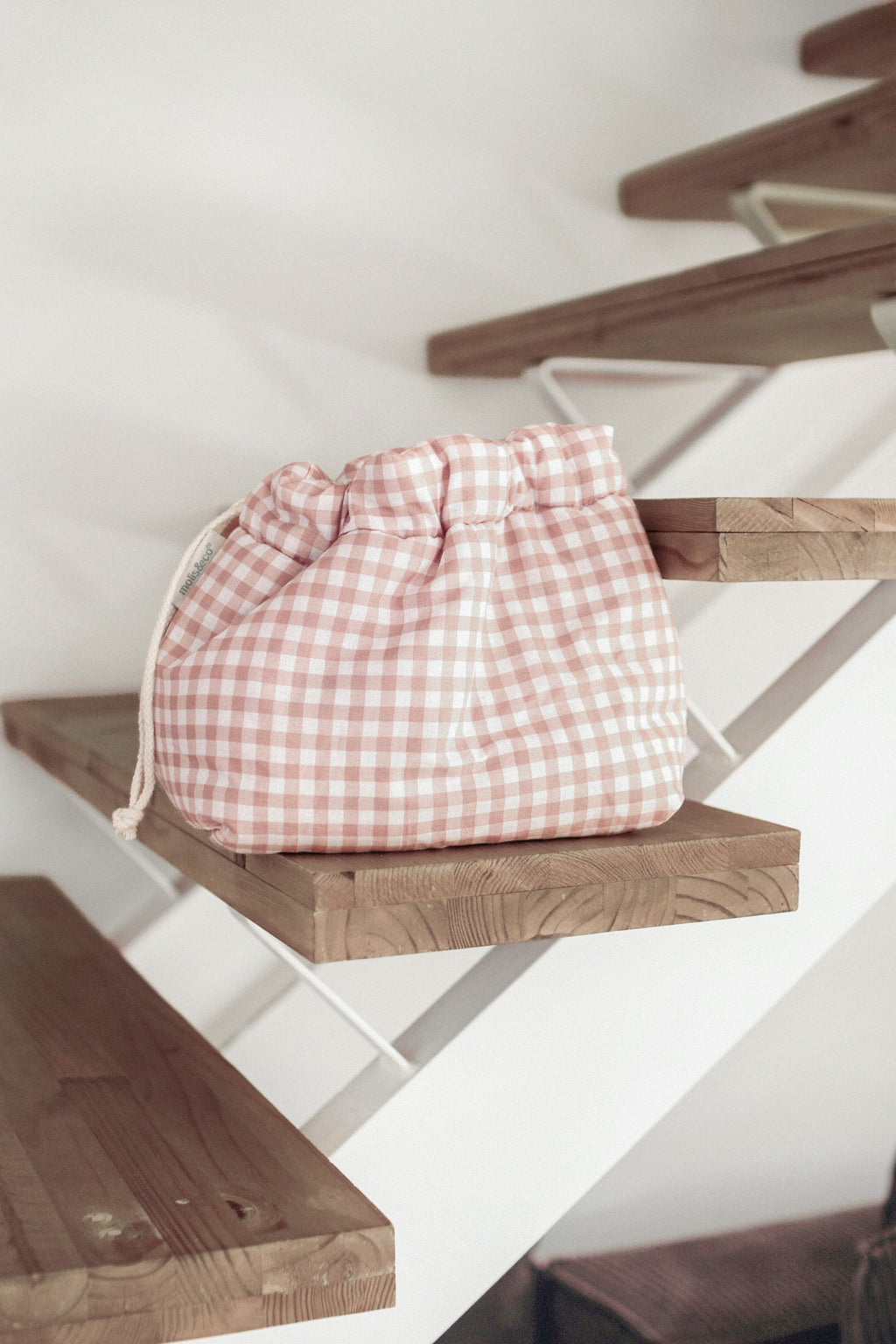 Organizador de mala de bebé MolisandCo Dusty Rose em ambiente de casa, ao lado dos complementos de um dia com o bebé