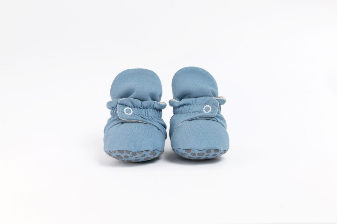 Pantufas botinhas azul-claras, exibidas de frente, com fecho de mola e tecido macio.
