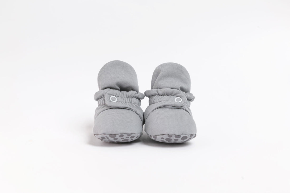 Pantufas botinhas cinza para bebé, apresentadas com vista frontal, com fecho de mola e tecido confortável.
