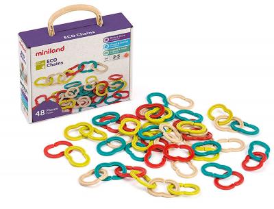 Conjunto Miniland Eco Chains de 48 peças coloridas, incluindo elos vermelhos, amarelos, azuis-esverdeados e creme, espalhados ao lado da caixa de arrumação roxa com pega de madeira.