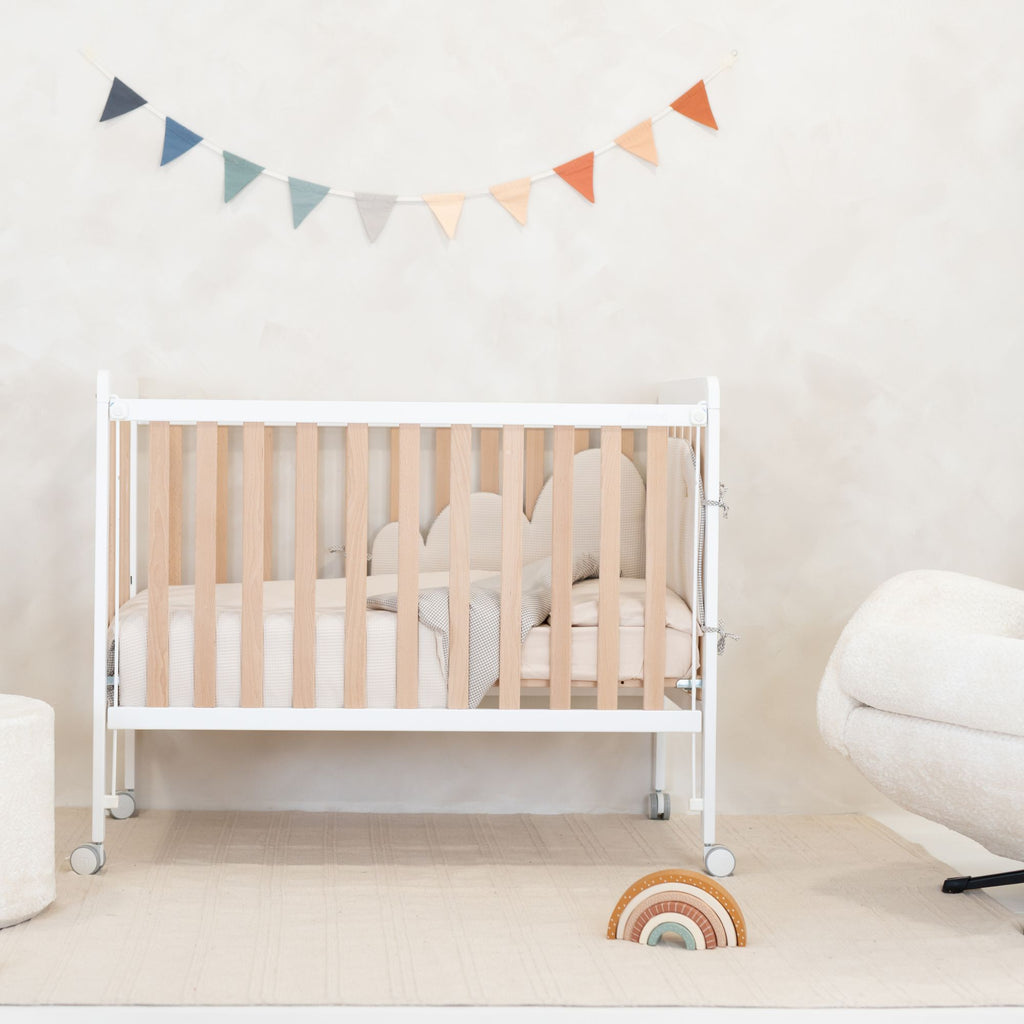 Berço de bebé branco decorado com o kit nórdico e protector Micuna Lauki em Beige, num quarto de bebé