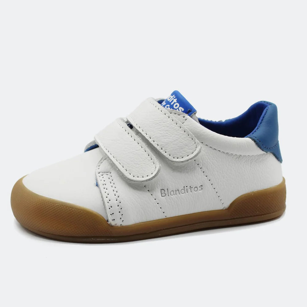 Vista lateral das sapatilhas barefoot Blanditos by Crio's Londres em pele branca com detalhes azuis, sola de borracha e duas tiras de velcro.