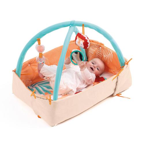 Ludi Tapete de Atividades Leão montado como mini-parque com um bebé sorridente a interagir com os brinquedos.