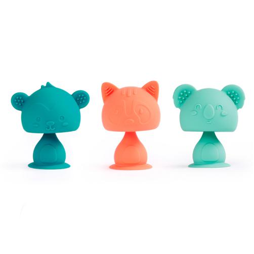 Três Ludi Animais com ventosa em silicone: um macaco azul-esverdeado, um guaxinim laranja e um koala verde-água, alinhados sobre um fundo branco.