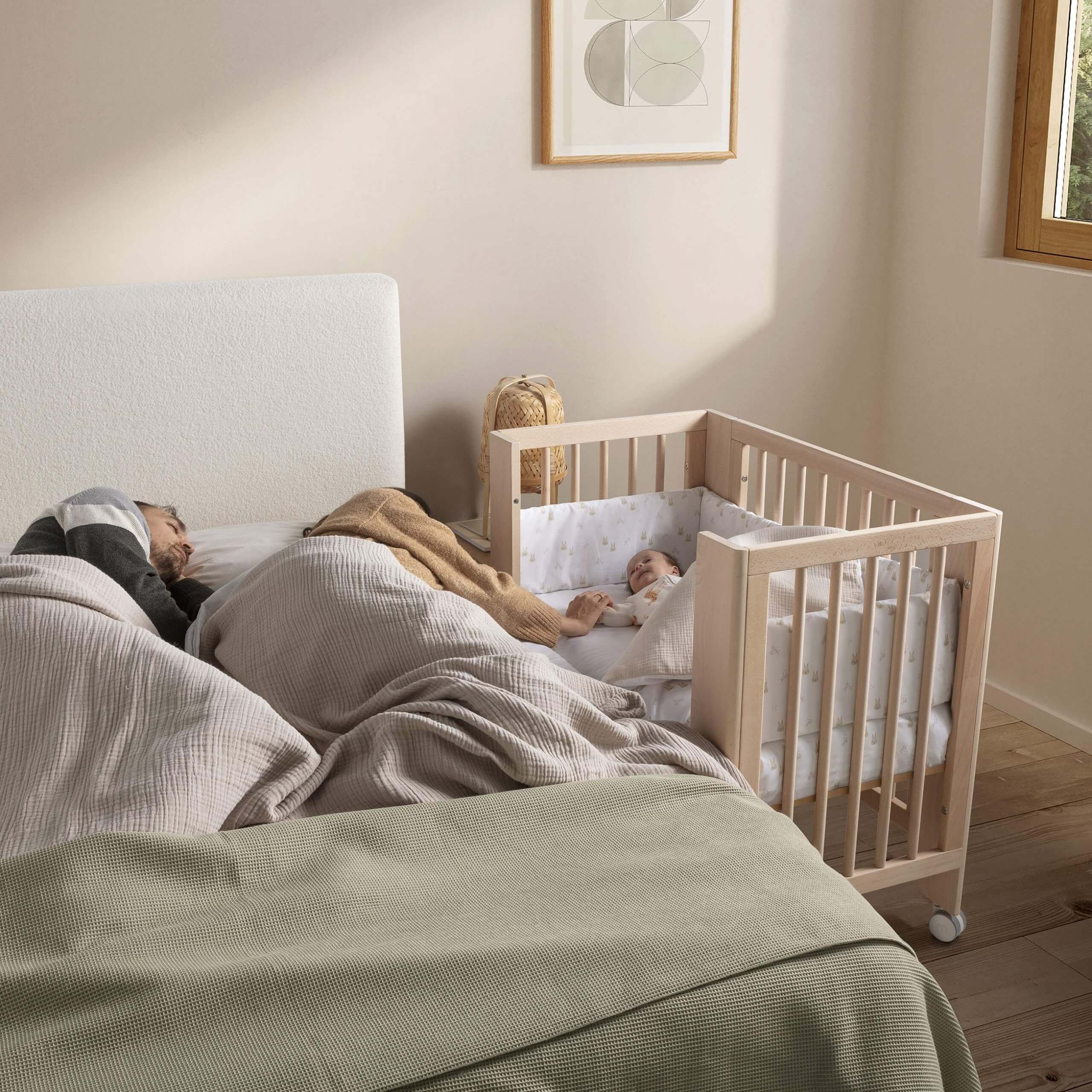 Bebé a dormir confortavelmente numa minicuna Micuna Mini Converbaby 90x50 com o Kit nórdico + protector Micuna Rabbits, ao lado da cama dos pais.