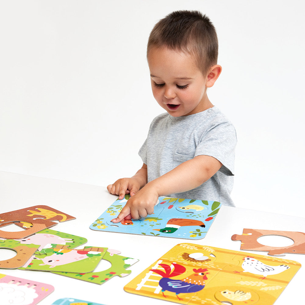 Criança a brincar com o Banana Panda Puzzle de Correspondência Animais da Quinta, apontando para um pato num dos puzzles.
