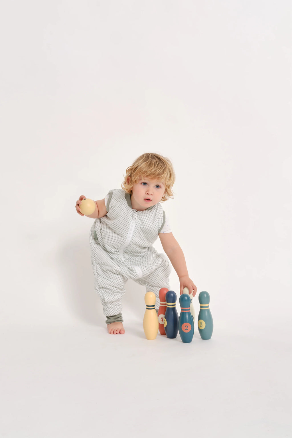 Criança a brincar com pinos de bowling, vestindo o saco de dormir MolisandCo TOG 1.0 com pés VICHY GREEN, enfatizando a liberdade para atividades.