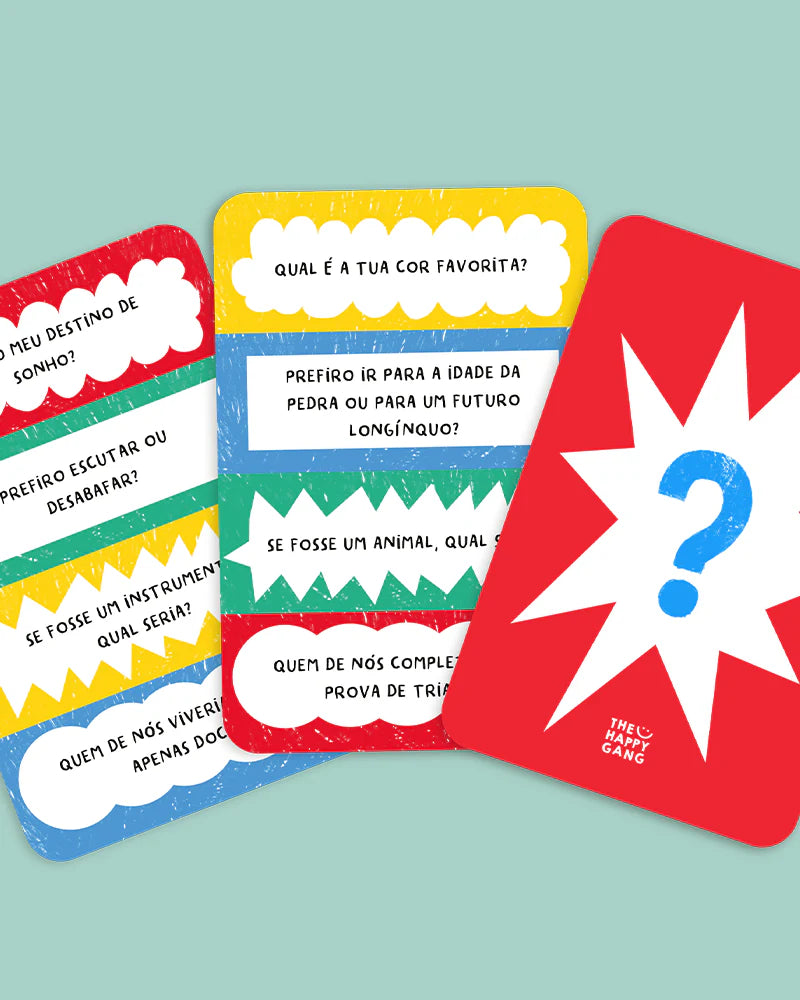 Detalhe de algumas cartas de perguntas do jogo "THE HAPPY GANG - Party Gang - A Grande Batalha", com ilustrações e texto como "QUAL É A TUA COR FAVORITA?", "PREFIRO IR PARA A IDADE DA PEDRA OU PARA UM FUTURO LONGÍNQUO?".