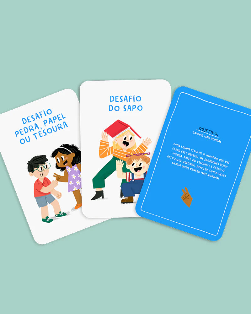 Detalhe de algumas cartas de desafios do jogo "THE HAPPY GANG - Party Gang - A Grande Batalha", como "DESAFIO PEDRA, PAPEL OU TESOURA", "DESAFIO DO SAPO" e uma carta azul com o objetivo do jogo.