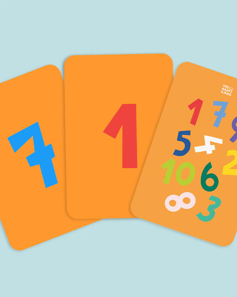 Três cartas de números do jogo Telefone Estragado, em tons de laranja, com grandes números coloridos como "7", "1" e uma mistura de vários dígitos.