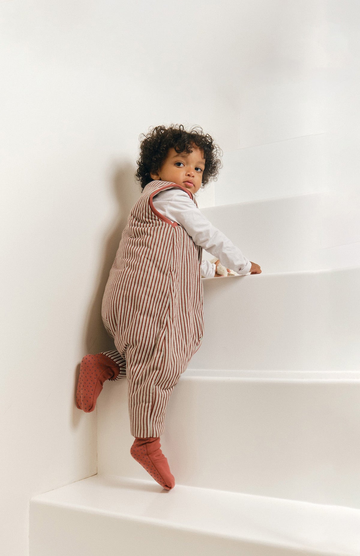 Pijama manta MolisandCo TOG 2.5 com pés e meias antiderrapantes na cor Burgundy Stripes, vestido por uma criança