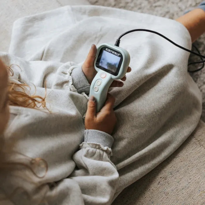 Vista superior de uma criança a utilizar a câmara flexível KidyWolf, observando o ecrã integrado enquanto explora.