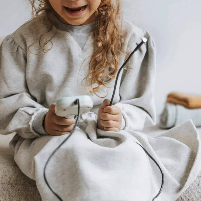 Criança com cabelo encaracolado a segurar o dispositivo KidyWolf, focada na exploração com o cabo flexível.