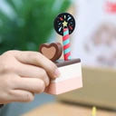 Mão de uma criança a segurar uma fatia do Classic World Bolo de Chocolate de madeira com uma decoração em forma de coração.
