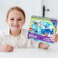 Menina feliz a mostrar o livro de atividades Totum Sticker by Number do Stitch, com autocolantes coloridos.
