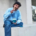 Homem jovem sentado ao ar livre, a comer uma refeição quente diretamente de um Termos para Sólidos Kambukka Bora 600ml azul-esverdeado.