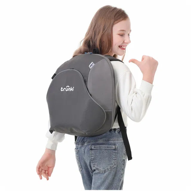 Criança sorridente a usar a Trunki BoostApak cinzenta como mochila, mostrando as alças de transporte de tamanho infantil e o logótipo Trunki.
