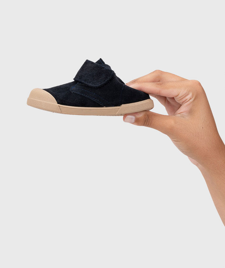 Mão a segurar uma bota Igor Barefoot Tui Marino, destacando o seu design leve e compacto.