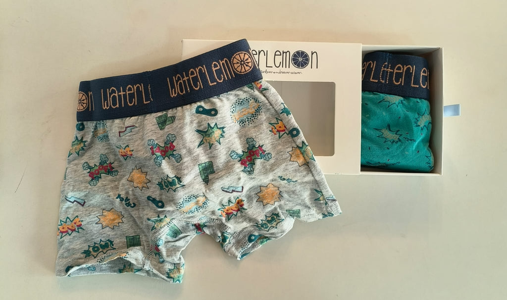 Boxer Waterlemon cinzento com padrão de banda desenhada e uma caixa aberta com outro boxer verde de banda desenhada.